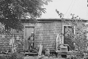 In other instances, existing buildings were used for housing. Here a depot construction worker is shown in a converted wood shed used as shelter.